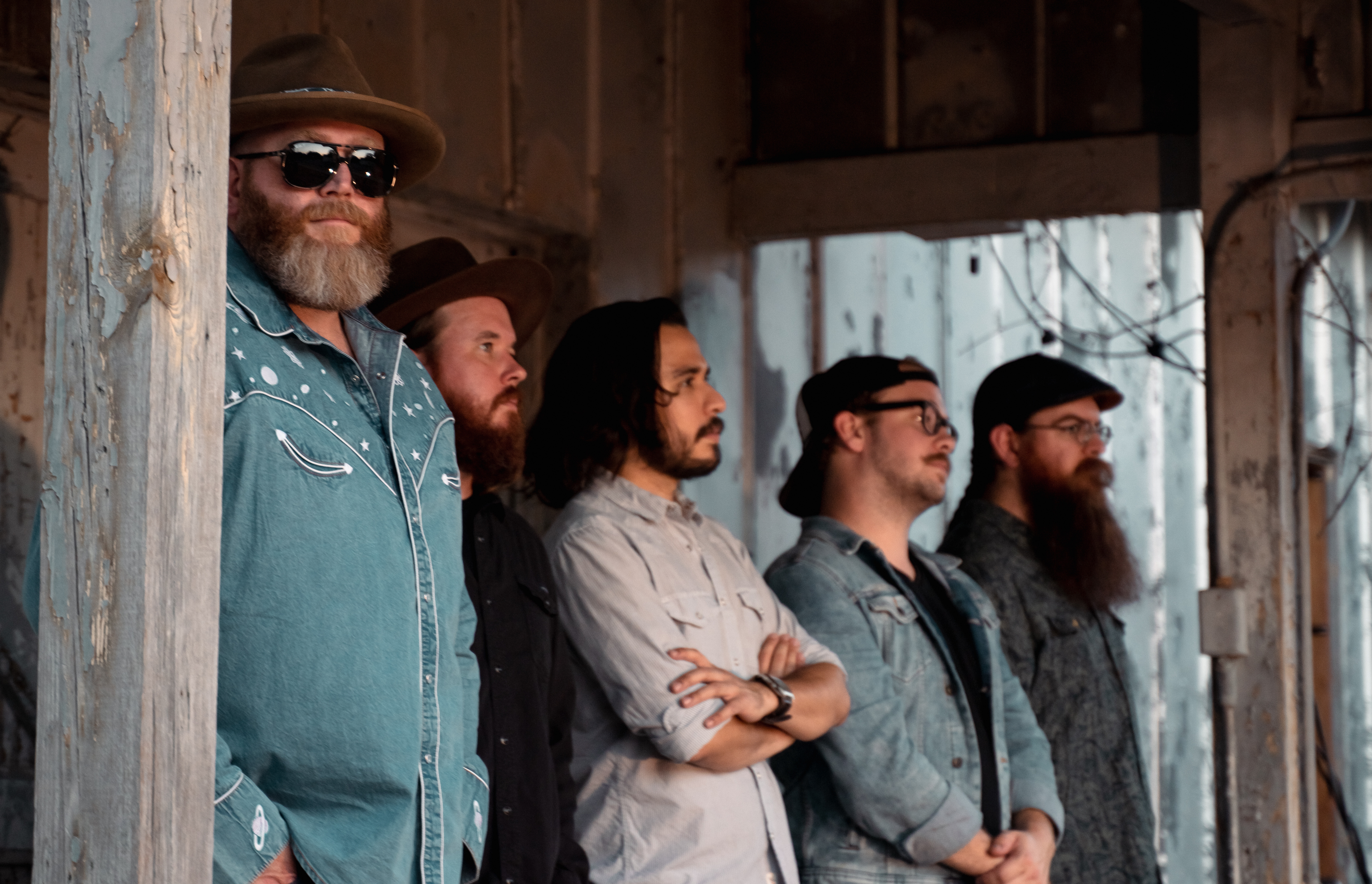 Memphis and the band standing dramatically on a rustic porch